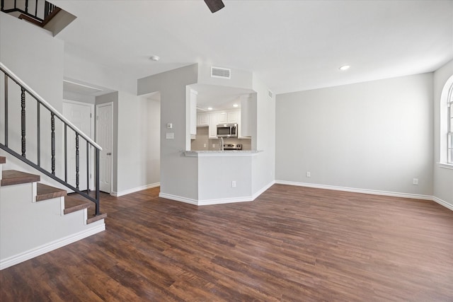 unfurnished living room featuring stairs, dark wood-style floors, recessed lighting, and baseboards