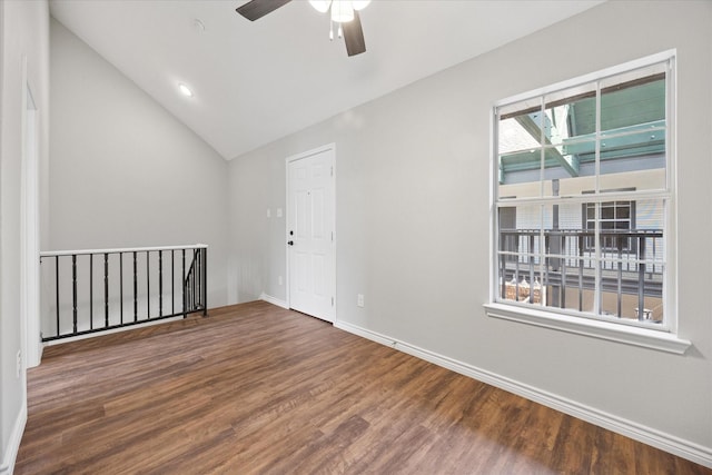 spare room with wood finished floors, lofted ceiling, a ceiling fan, and baseboards