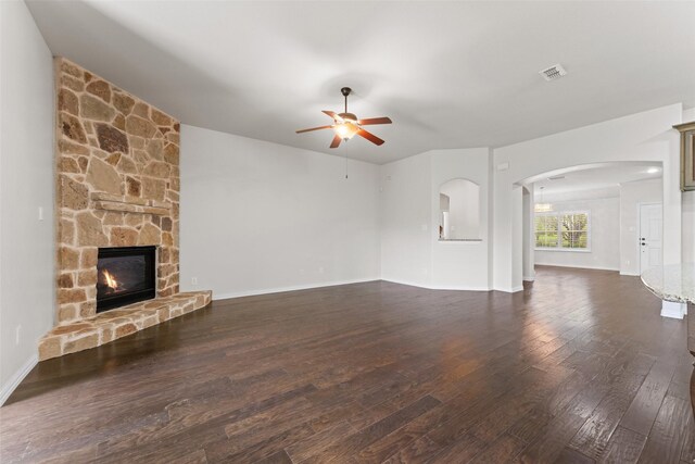 109 Joplin Dr, Mckinney, TX 75071 - unfurnished living room with visible vents, arched walkways, a stone fireplace, a ceiling fan, and dark wood finished floors