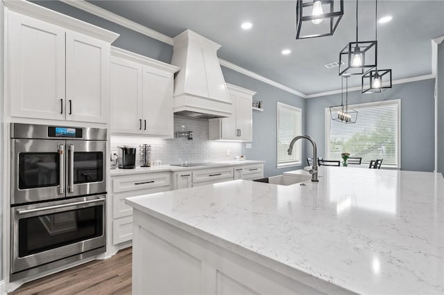 10281 Creekside Ln, Waco, TX 76712 - kitchen featuring a sink, double oven, premium range hood, decorative backsplash, and white cabinets
