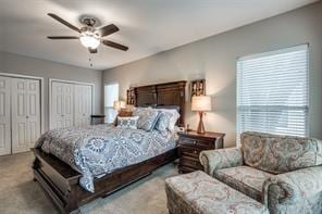carpeted bedroom featuring two closets and ceiling fan