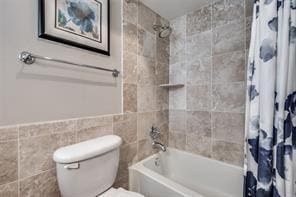 bathroom featuring toilet, shower / bath combo, and tile walls