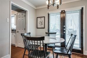 dining space with dark wood-type flooring, baseboards, an inviting chandelier, and ornamental molding