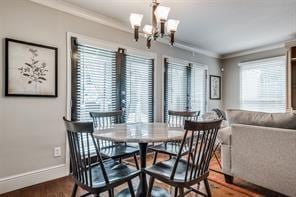 dining area featuring a chandelier, wood finished floors, baseboards, and ornamental molding