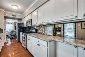 kitchen featuring white cabinetry, ornamental molding, appliances with stainless steel finishes, and wood finished floors