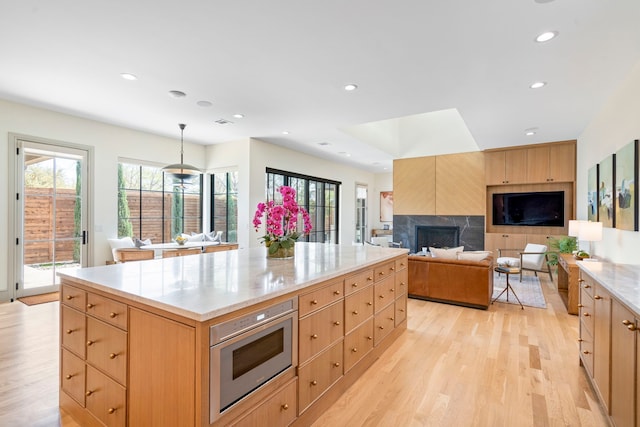 7158 Pasadena Ave, Dallas, TX 75214 - kitchen featuring light brown cabinetry, stainless steel microwave, light wood-style floors, plenty of natural light, and recessed lighting