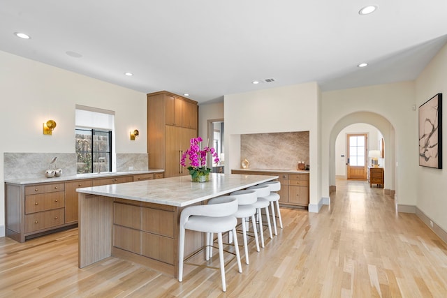 7158 Pasadena Ave, Dallas, TX 75214 - kitchen featuring arched walkways, a spacious island, light wood-type flooring, backsplash, and recessed lighting
