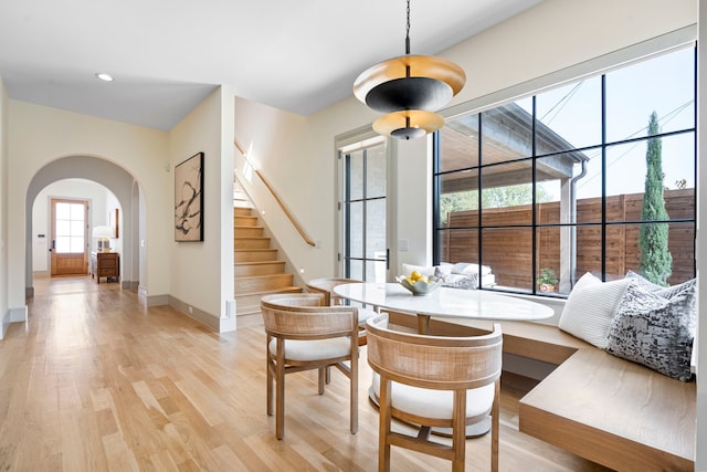 7158 Pasadena Ave, Dallas, TX 75214 - kitchen featuring arched walkways, light wood-style floors, a spacious island, decorative backsplash, and a kitchen breakfast bar