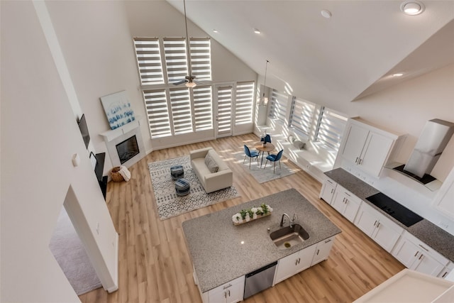 1108 Silverthorn Trl, Justin, TX 76247 - living area with high vaulted ceiling, light wood-style flooring, a glass covered fireplace, a ceiling fan, and recessed lighting