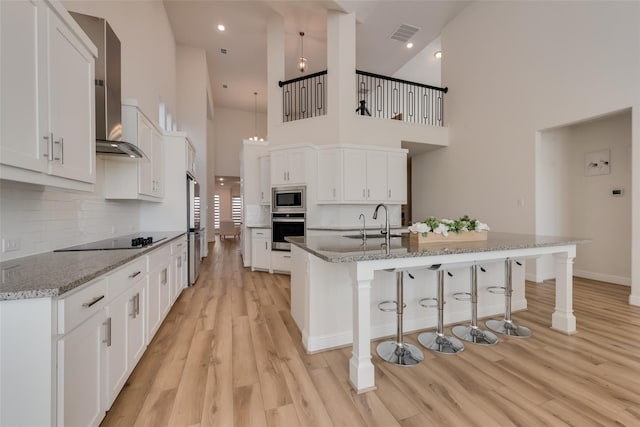 1108 Silverthorn Trl, Justin, TX 76247 - kitchen featuring stainless steel microwave, a high ceiling, black electric stovetop, a sink, and a breakfast bar area