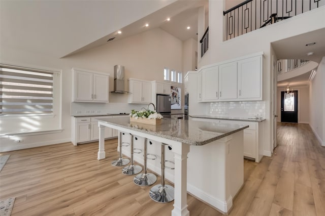 1108 Silverthorn Trl, Justin, TX 76247 - kitchen featuring a towering ceiling, a breakfast bar, wall chimney exhaust hood, freestanding refrigerator, and white cabinets