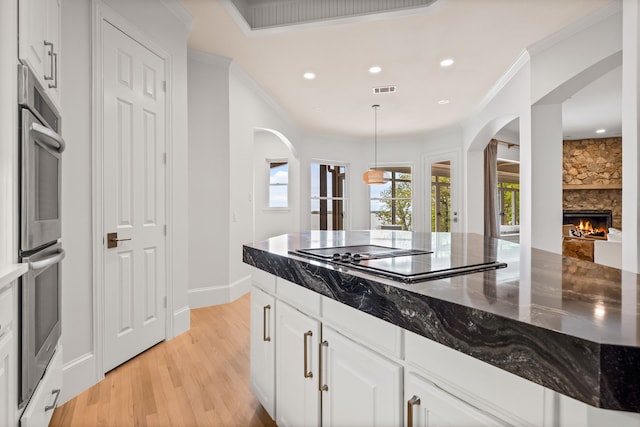 1190 Emerald Sound Blvd, Oak Point, TX 75068 - kitchen featuring arched walkways, black electric stovetop, light wood finished floors, dark stone counters, and recessed lighting