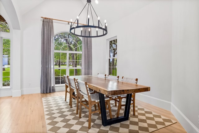 1190 Emerald Sound Blvd, Oak Point, TX 75068 - dining area with a chandelier, light wood finished floors, baseboards, arched walkways, and high vaulted ceiling