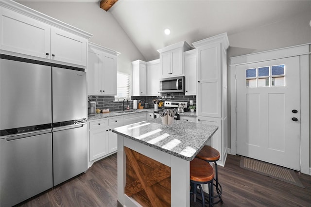 12908 County Road 463, Tyler, TX 75706 - kitchen with dark wood-type flooring, tasteful backsplash, appliances with stainless steel finishes, a sink, and vaulted ceiling with beams