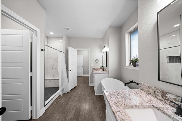 12908 County Road 463, Tyler, TX 75706 - full bath featuring two vanities, a shower stall, a freestanding tub, wood finished floors, and a sink