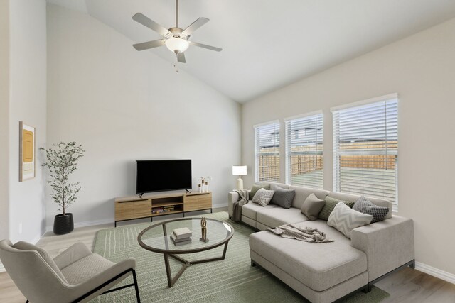 living area with baseboards, high vaulted ceiling, a ceiling fan, and wood finished floors