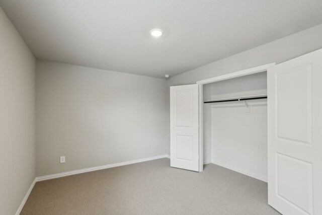 unfurnished bedroom featuring a closet, light carpet, and baseboards