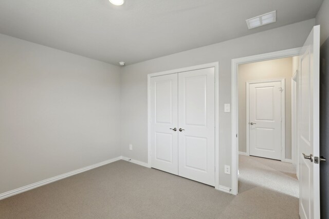 unfurnished bedroom with carpet, baseboards, a closet, and visible vents