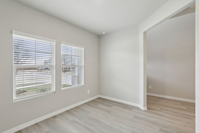 unfurnished room featuring baseboards and light wood-type flooring
