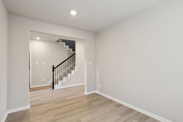 empty room with light wood finished floors, recessed lighting, baseboards, and stairs