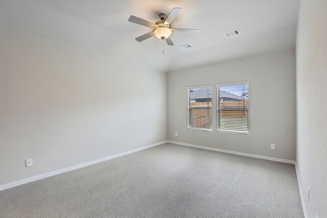 carpeted empty room with baseboards, a ceiling fan, and visible vents