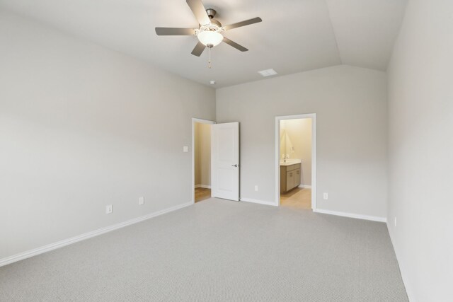 unfurnished bedroom featuring visible vents, baseboards, ensuite bath, light carpet, and lofted ceiling