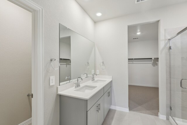 bathroom with a shower stall, a sink, and a walk in closet