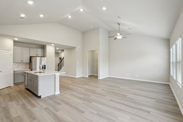 kitchen featuring light countertops, an island with sink, stainless steel appliances, visible vents, and gray cabinetry