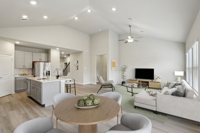 living area featuring light wood-type flooring, visible vents, ceiling fan, and stairs