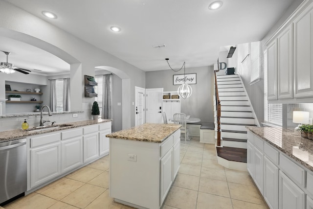 7520 Harvest Bend Ln, Sachse, TX 75048 - kitchen featuring stainless steel dishwasher, a sink, a kitchen island, white cabinetry, and arched walkways