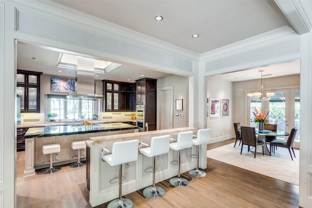 10989 Crooked Creek Dr, Dallas, TX 75229 - kitchen with a kitchen breakfast bar, wood finished floors, a kitchen island, crown molding, and stainless steel double oven