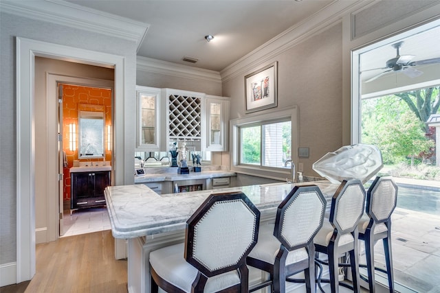 10989 Crooked Creek Dr, Dallas, TX 75229 - kitchen featuring a breakfast bar area, glass insert cabinets, white cabinetry, crown molding, and a sink