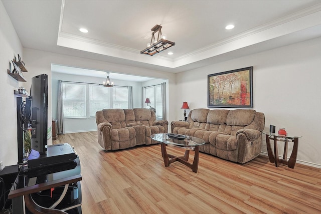 living room featuring light wood-type flooring, a chandelier, crown molding, a tray ceiling, and recessed lighting