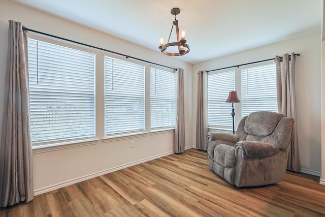 living area with baseboards, an inviting chandelier, and wood finished floors