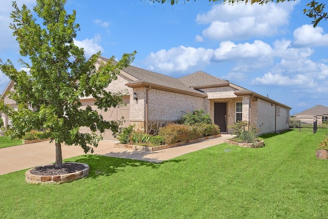 view of front of house featuring a front yard, a shingled roof, fence, brick siding, and driveway