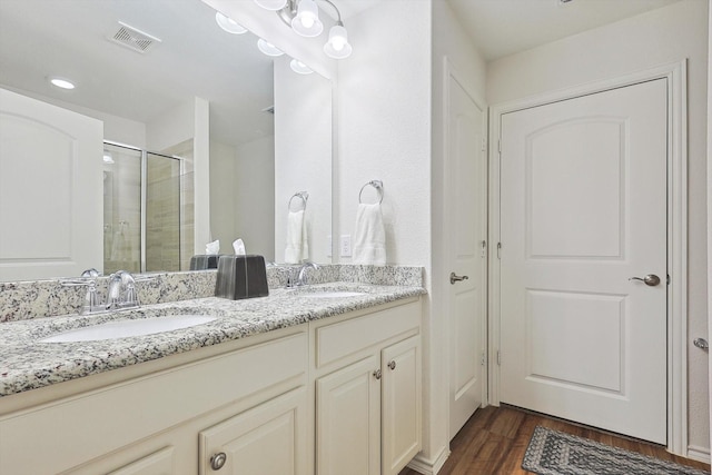 full bath featuring a sink, visible vents, a shower stall, and wood finished floors