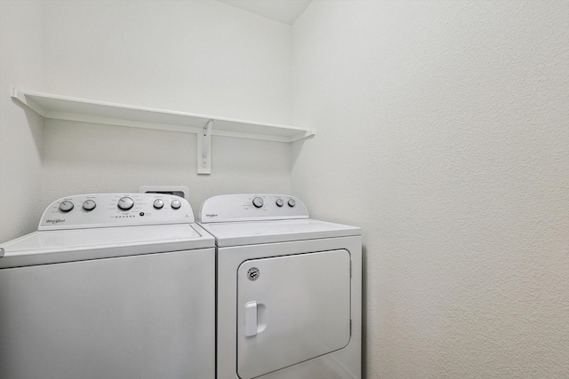 laundry room featuring a textured wall, washer and clothes dryer, and laundry area