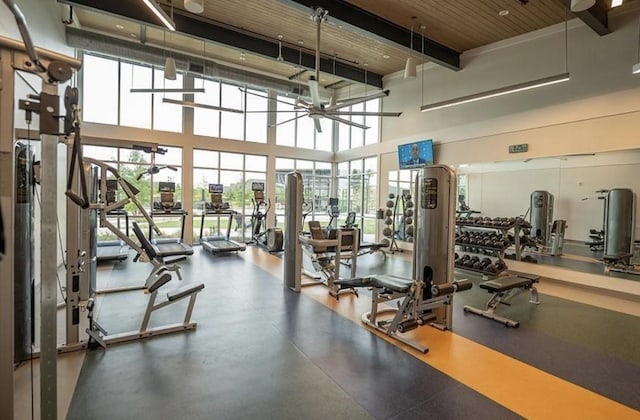 gym featuring a towering ceiling and a ceiling fan