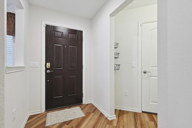 foyer entrance featuring baseboards and wood finished floors