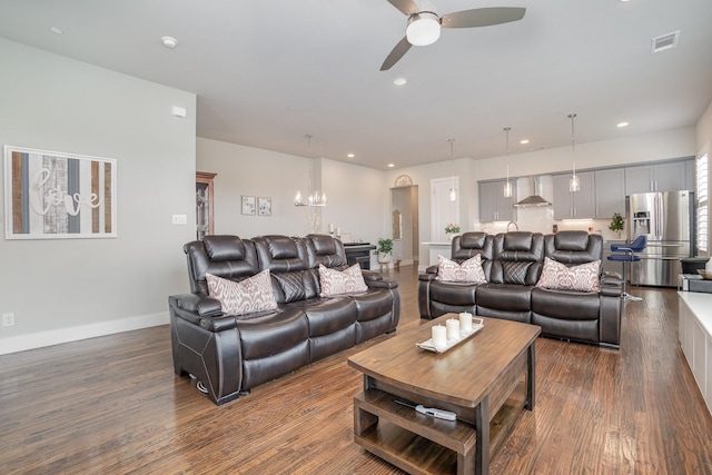 living area featuring dark wood-type flooring, visible vents, recessed lighting, and ceiling fan with notable chandelier
