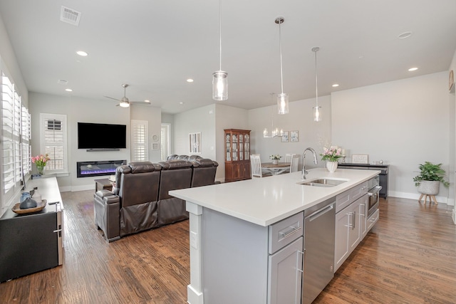 kitchen featuring wood finished floors, a sink, stainless steel appliances, light countertops, and baseboards