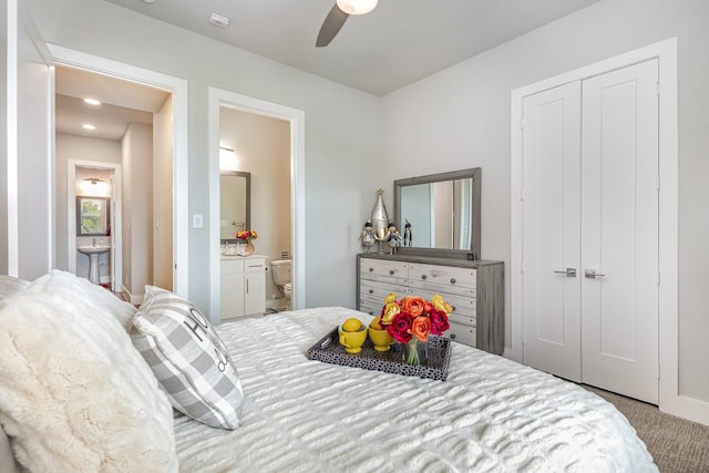 carpeted bedroom with ensuite bath, a ceiling fan, and a closet