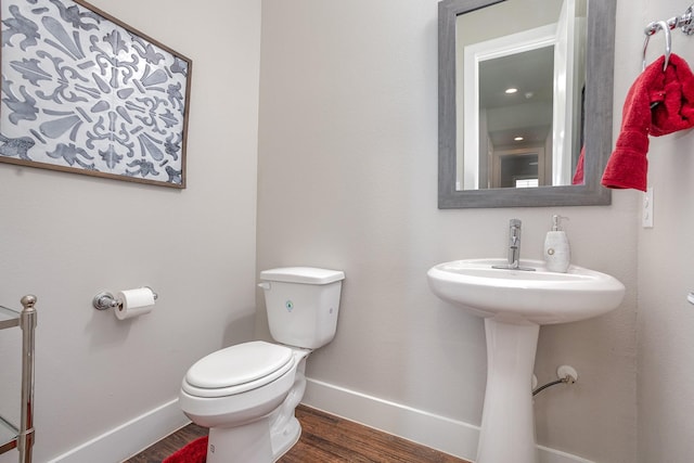 bathroom with baseboards, wood finished floors, and toilet
