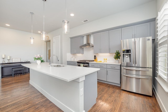 kitchen featuring wall chimney range hood, gray cabinetry, stainless steel appliances, and a sink