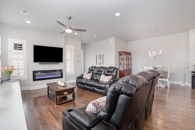 living area with baseboards, visible vents, ceiling fan with notable chandelier, and dark wood-style flooring