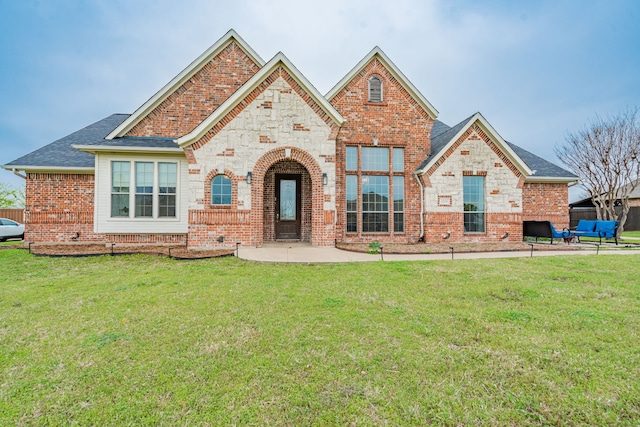view of front of home with a front yard, brick siding, and a patio