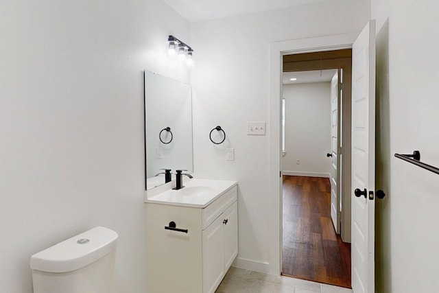 6840 Hillmont Dr, Dallas, TX 75217 - bathroom with toilet, vanity, wood finished floors, and baseboards