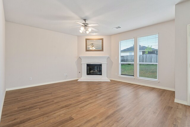 5013 Royal Burgess Dr, Fort Worth, TX 76135 - unfurnished living room featuring visible vents, baseboards, a glass covered fireplace, light wood-style flooring, and ceiling fan