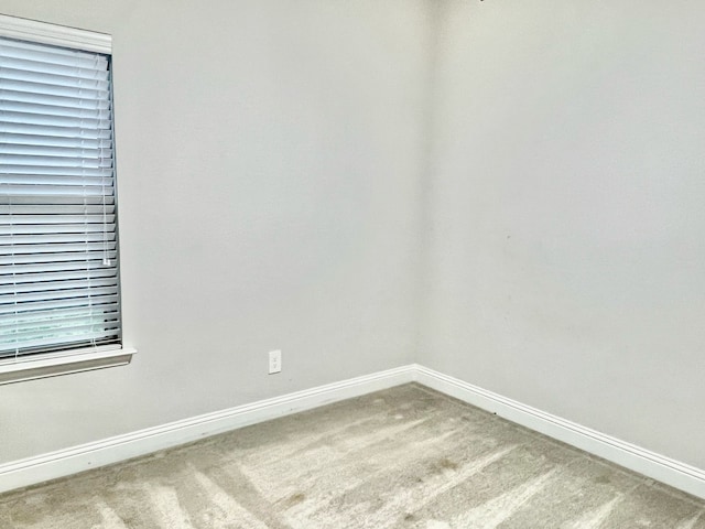 carpeted spare room featuring baseboards
