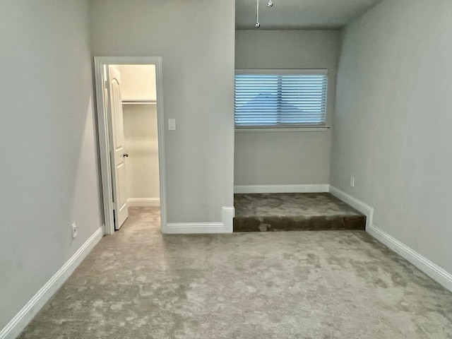 unfurnished bedroom featuring a spacious closet, carpet, and baseboards